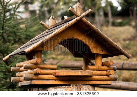 Birdhouse On A Tree Hanging From A Branch. Wooden Birdhouse Made Of Small Logs. Birdhouse On Blurred