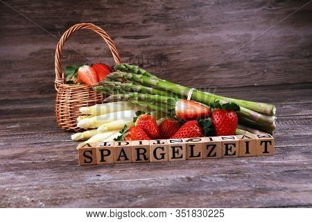 White And Green Asparagus With Strawberries On Rustic Background With Spargelzeit Wooden Letter.