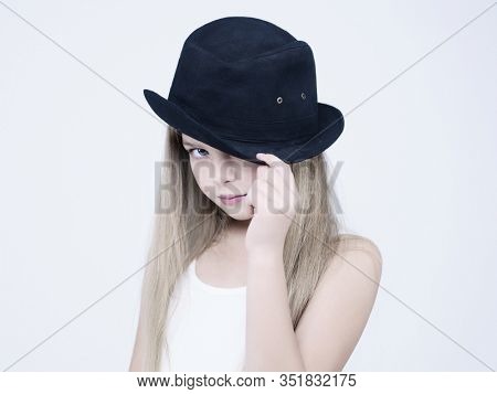 little pretty girl in black classic hat. Studio ashion photography of kid in white dress. Beautiul model on white background.