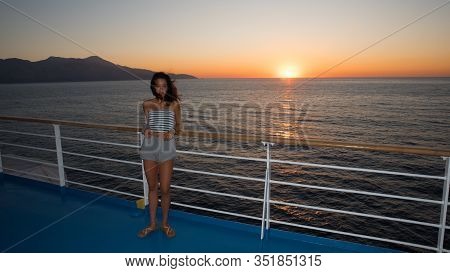 Asian Teen In Tube Top Standing On Deck Of Ferry Looking Away From Sunset On Ferry To Greece