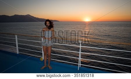Asian Teen In Tube Top Standing On Deck Of Ferry Looking Away From Sunset On Ferry To Greece