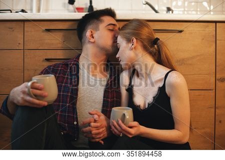 Charming Caucasian Couple Drinking Coffee In The Morning On The Floor Enjoying Their Moment Being To