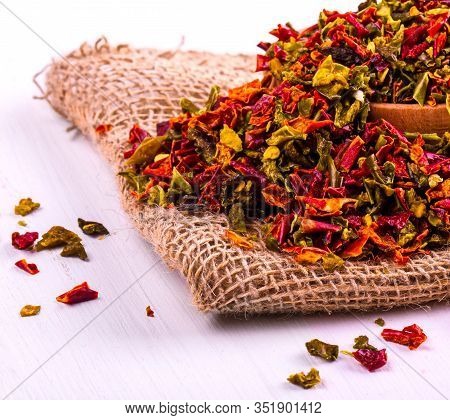 The Colored With Pepper In A Cup And Burlap On A Wooden Table