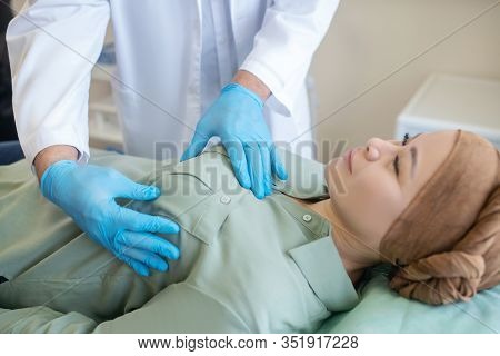 Mammologist In Blue Protective Gloves Palping Breast Of His Patient