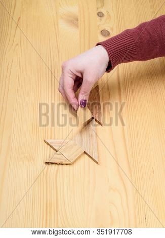 Girl Collects A Wooden Tangram Puzzle On A Wooden Table.