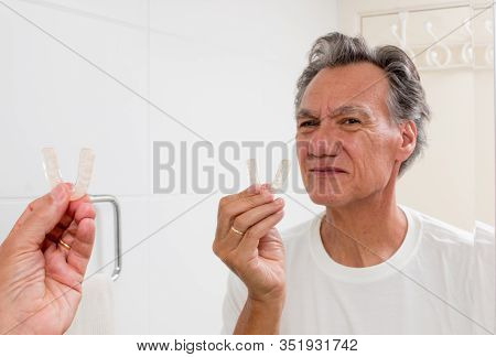 Man Examine His Night Guard In Front Of A Mirror