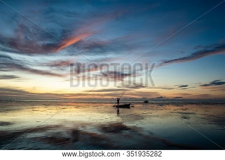 Silhouette Of A Person Holding A Long Stick To Push The Canoe In The Water Column