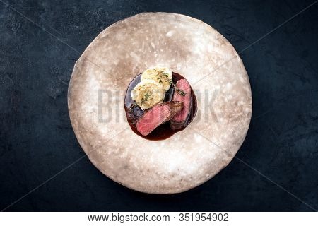 Fried dry aged venison tenderloin fillet medallion steak natural with bread dumpling and spicy gravy sauce as top view on a modern design plate with copy space 