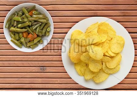 Potato Chips On A White Plate With Vegetarion Salad. Chips On A Orange Wooden Background Top View.
