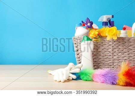 Wicker Basket With Spring Flowers And Cleaning Supplies On Wooden Table. Space For Text