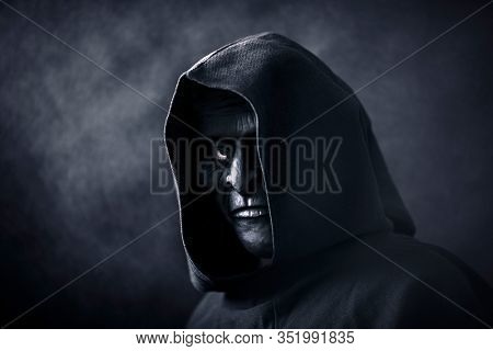 Scary figure in hooded cloak with mask
