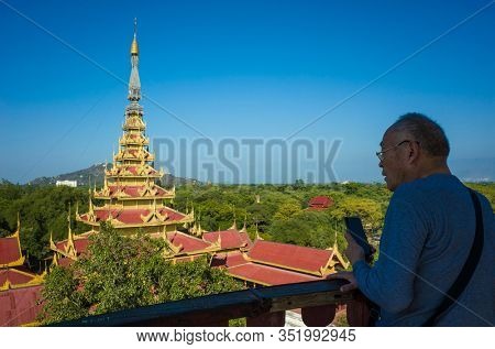 Mandalay, Myanmar - January 8, 2019: Asian senior tourist observing Mandalay Palace from watchtower