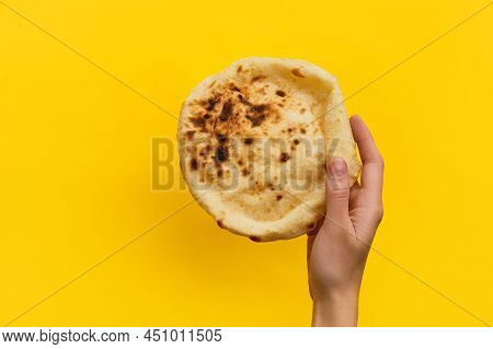 Egyptian Bread Aish Baladi. Womans Hand Holding Fresh Bread Over Yellow Background