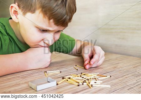A Child Looks And Plays With Matches, A Dangerous Activity For A Toddler At Home