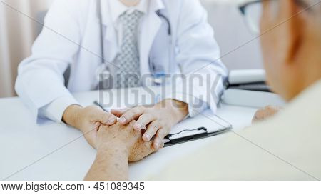 Hand Of Doctor Comforting Patient At Consulting Room. Doctor And Patient Are Discussing Consultation