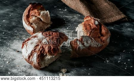 a round kamut wheat bread loaf broken in some pieces on a mottled dark gray fabric surface