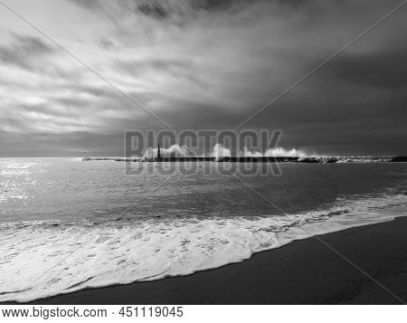 Giant Waves Breaking On The Breakwater And The Lighthouse On Aguda Beach, Miramar, Arcozelos Town