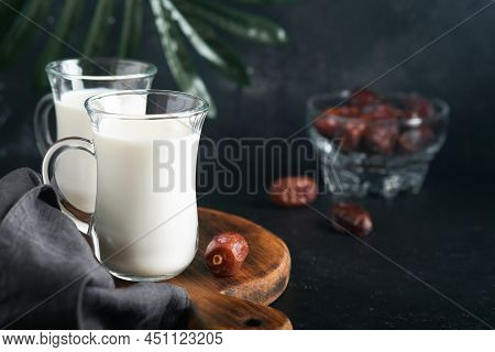 Ramadan Kareem Food And Drinks. Plate Of Dates, Glass Of Milk And Date Palm Branch On Black Backgrou