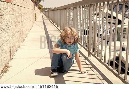 Boy Child Take Short Break Hunkering Down On Promenade, Rest