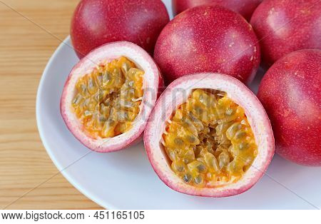 Mouthwatering Cut In Half Ripe Passion Fruit With Heap Of Whole Fruits In The Backdrop