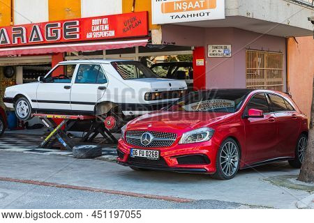 Antalya; Turkey - March 04 2022: Yellow Tofas Dogan Car On A Lift At A Tire Shop  And Red  Mercedes-