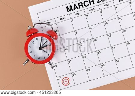 Concept For Time Change For Central European Summer Time On March 27th With Red Alarm Clock And Cale