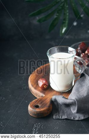 Ramadan Kareem Food And Drinks. Plate Of Dates, Glass Of Milk And Date Palm Branch On Black Backgrou
