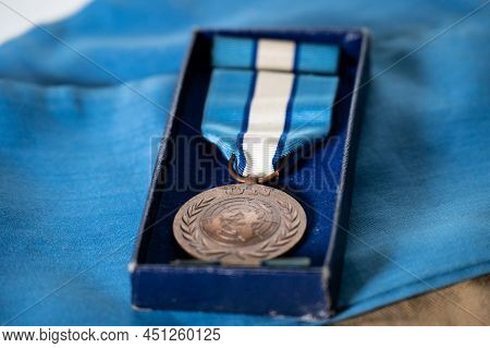 Shallow Focus Shot Of A United Nations Peacekeeper's Medal And Service Ribbon In Box On A Blue Un Cr
