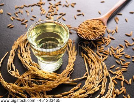 Rice Bran Oil In Glass With Seed Grain On Wooden Background. Organic Meal Ingredient Raw Food For Co