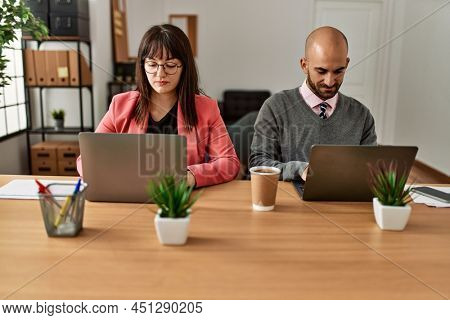 Two hispanic business workers with serious expressios working at the office.