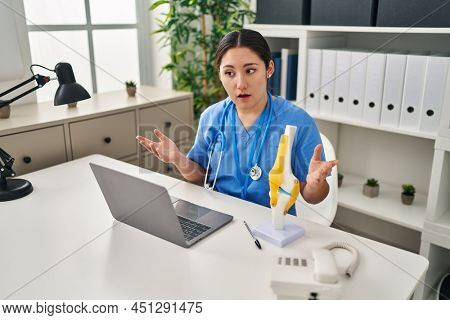 Young hispanic woman wearing doctor uniform having teleconsultation at clinic