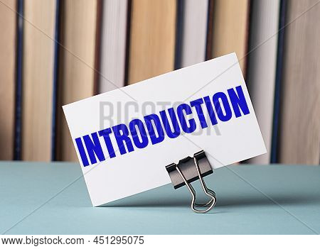 A White Card With The Text Introduction Stands On A Clip For Papers On The Table Against The Backgro
