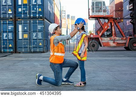 Father And Little Daughter Wearing A Safety Helmet At Container Cargo Site. Business Heir Concept. H