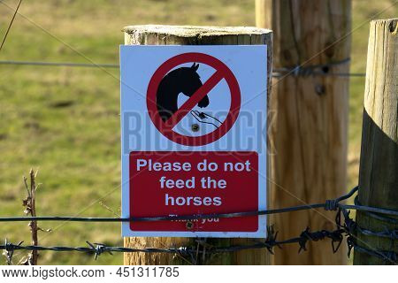 Please Do Not Feed The Horses Sign Nailed To A Paddock Fence Post