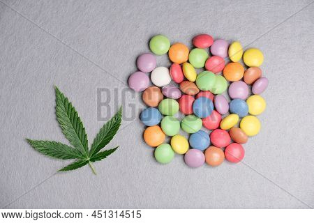 Cannabis Leaf With Colorful Candy Confetti Close Up. Marijuana Sweets With Cbd And Thc On Gray 
Back