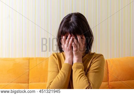 Upset Crying Middle Aged Woman Suffering From Stress Covering Her Face With Her Hands On An Orange S