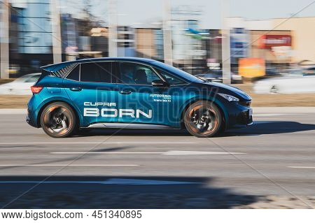 Cupra Born Driving Down The Street. Sporty Blue Car On The Street, Side View. Riga, Latvia - 16 Mar 