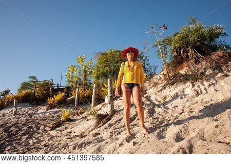 Lady Standing At The Top Of A Sand Dune At The River Beach Called Prianha In Caraiva, Bahia, Brazil