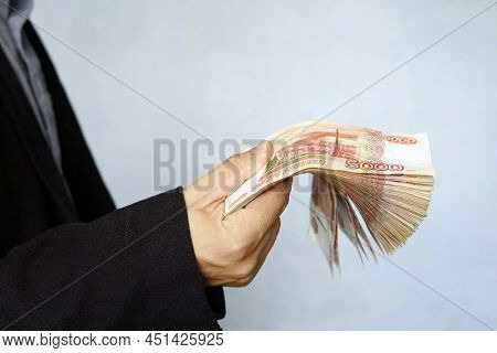 Man In Skirt Holds Russian Rubles Banknotes. Financial Theme. Horizontal View. A Large Wad Of Money 