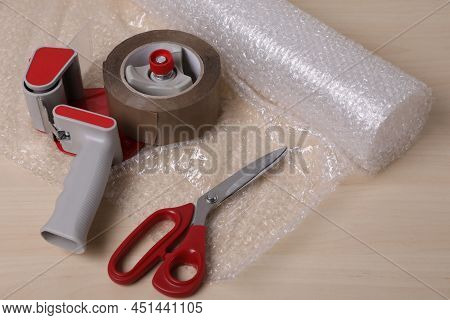 Roll Of Bubble Wrap, Scissors And Adhesive Tape On Wooden Table