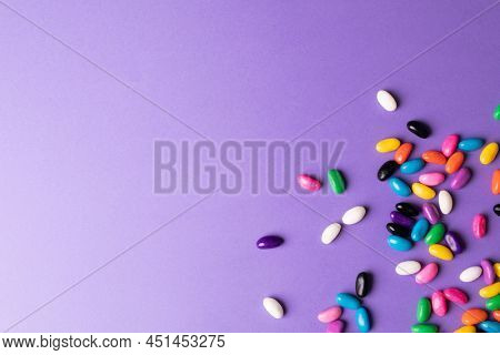 Directly above view of scatted multi colored candies on purple background with copy space. unaltered, sweet food and unhealthy eating concept.