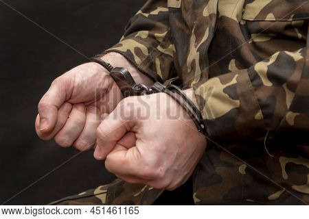 A Military Soldier In Handcuffs, Hands Behind His Back, On A Dark Background. Concept: War Criminal,