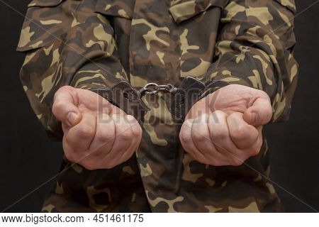 A Military Soldier In Handcuffs, Hands Behind His Back, On A Dark Background. Concept: War Criminal,