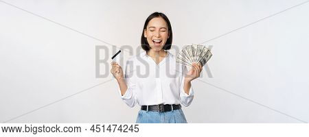 Finance And Money Concept. Happy Young Asian Woman Dancing With Cash And Credit Card, Smiling Please