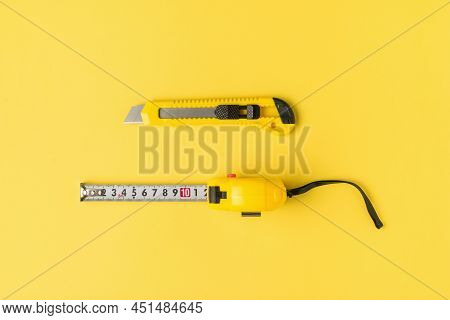 Yellow Measuring Tape And A Yellow Stationery Knife On A Yellow Background. Tools For Creativity. Fl