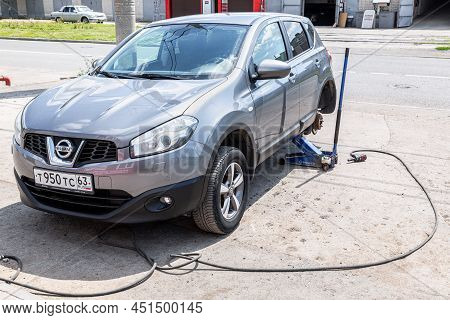Samara, Russia - July 4, 2021: Сar At The Tire Mounting With Removed Wheel On Pneumatic Jack. Season