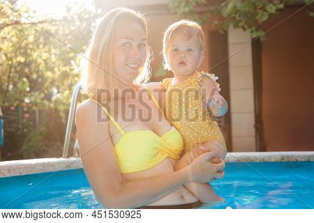 Portrait Of A Happy Caucasian Young Mother With A Her Lettle Daughter Standing In The Pool. Teaching