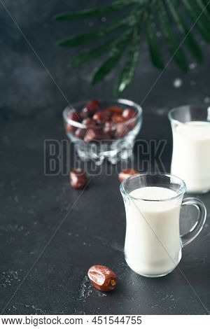 Ramadan Kareem Food And Drinks. Plate Of Dates, Glass Of Milk And Date Palm Branch On Black Backgrou