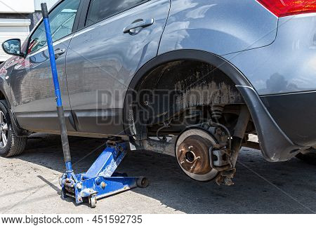 Сar At The Tire Mounting With Removed Wheel On Pneumatic Jack. Seasonal Tire Change. Car Service Con
