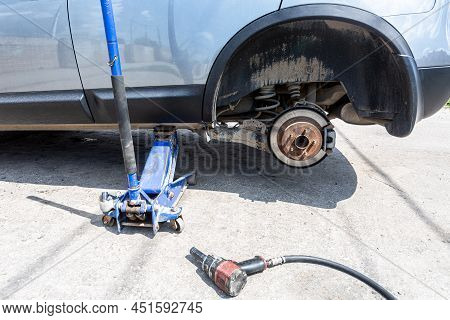Сar At The Tire Mounting With Removed Wheel On Pneumatic Jack. Seasonal Tire Change. Car Service Con